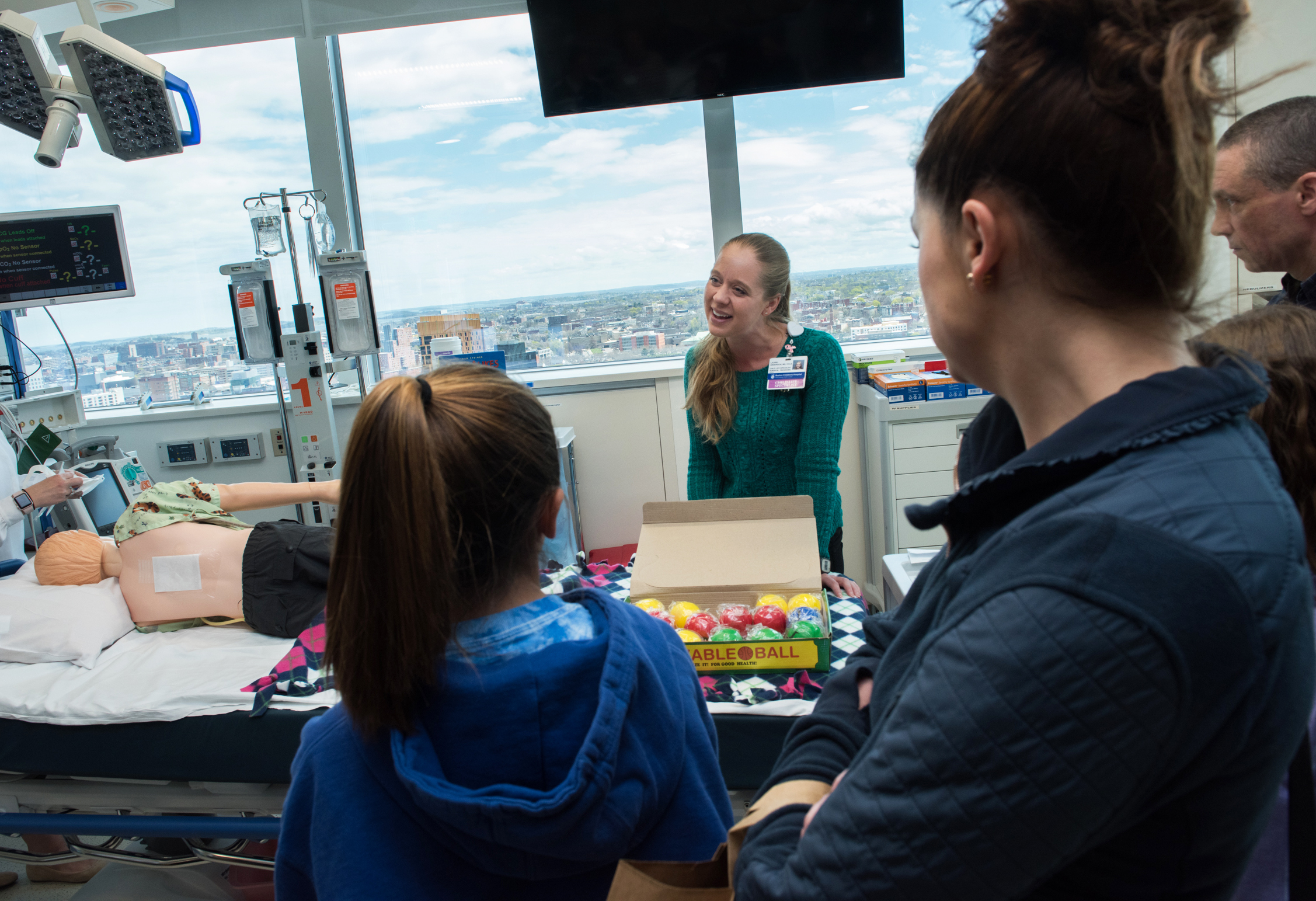 Parent caregivers and children observe a child life specialists explain an upcoming procedure.